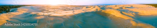 Fototapeta Naklejka Na Ścianę i Meble -  Wide aerial panorama of Anna Bay sand dunes at sunrise with one person. Anna Bay, New South Wales, Australia