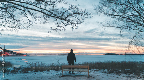 Silhouette man watching sunset over frozen sea
