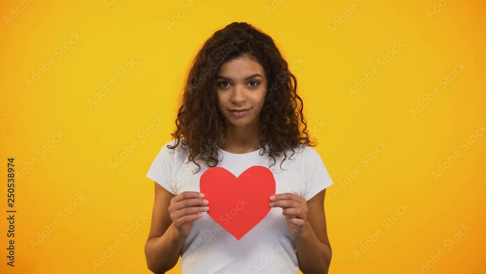 Kind mixed-race girl showing red paper heart on camera Valentines day, volunteer Kind mixed-race girl showing red paper heart on camera Valentines day, volunteer