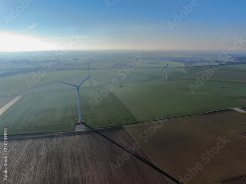Aerial view of wind turbines and agricultural fields on a beautiful blue winter day - Energy Production with clean and Renewable Energy - aerial shot, analog image style
