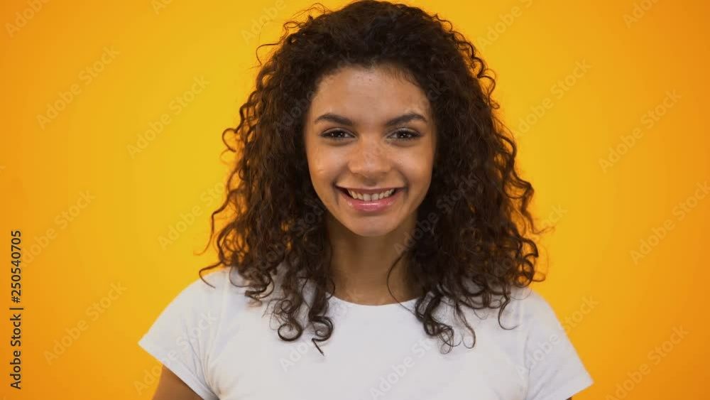 Cheerful curly-haired girl putting orange slices on eyes and smiling, vitamin c