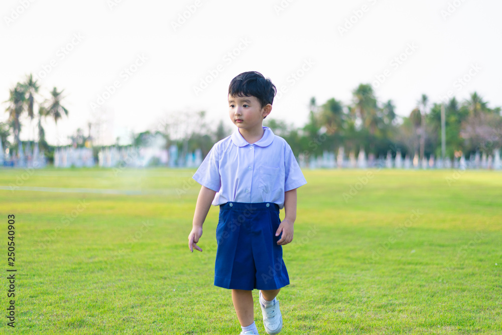 Outdoor portrait of a Lonely Asian student kid in school uniform standing.