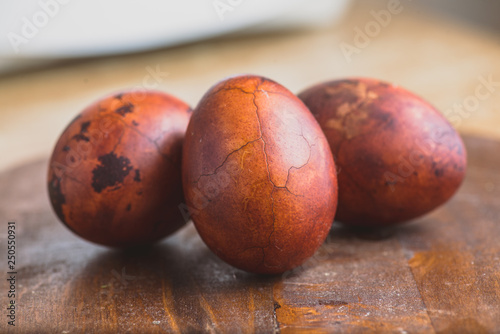 Easter eggs on wooden background. Painted brown with spots and cracks. Selective focus macro shot with shallow DOF