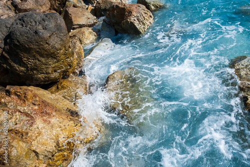 blue waves break on the rocks of the shore