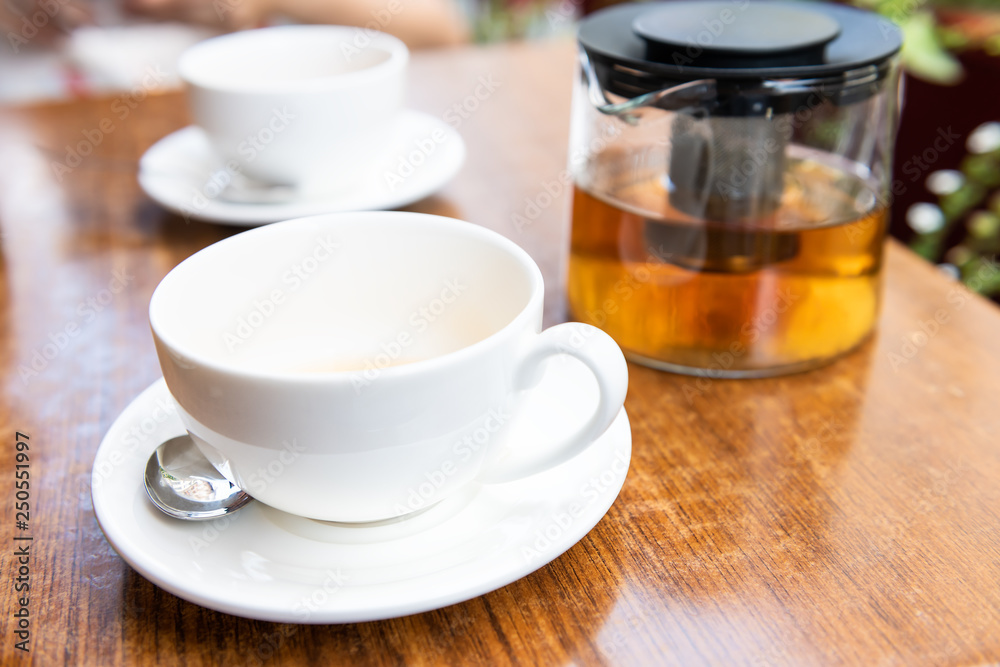 Closeup of two white cups on plates and green black or oolong tea in breakfast brunch cafe restaurant wooden table with spoon Closeup of two white cups on plates and green black or oolong tea in breakfast brunch cafe restaurant wooden table with spoon