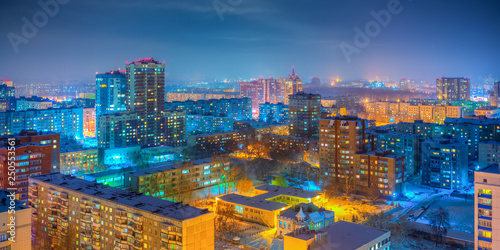 Urban panorama. Beautiful top view of the city. Colorful street lighting of the night metropolis. Many high-rise buildings. Cold winter weather. Novosibirsk, Siberia, Russia. photo