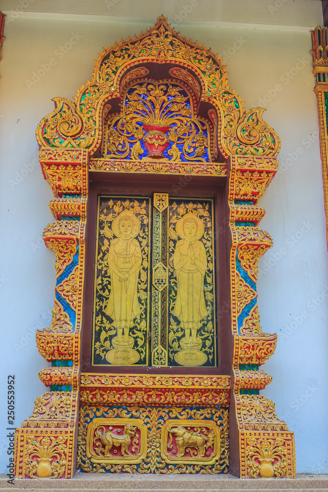 Beautiful Thai's style temple windows with golden craved buddha on the window panels.