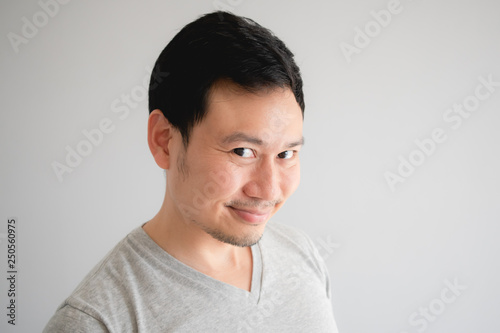 Fotografie Funny tricky awkward smirk face of man in grey t-shirt.