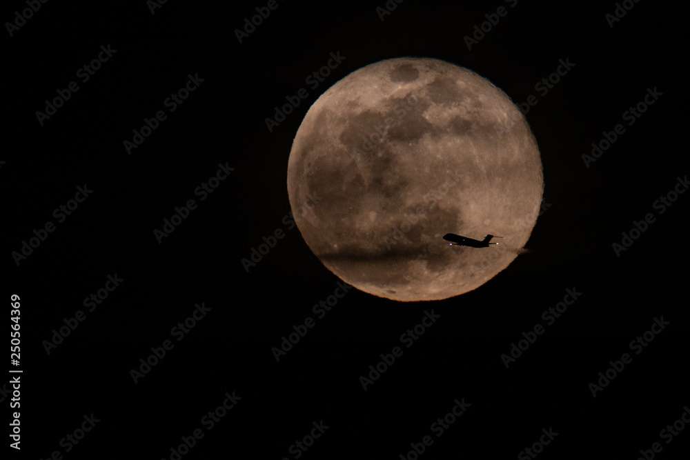 Obraz premium Full moon with a plane passing by