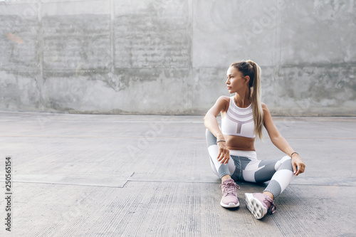 Fototapeta Naklejka Na Ścianę i Meble -  Fitness sport model in fashion sportswear posing over gray wall