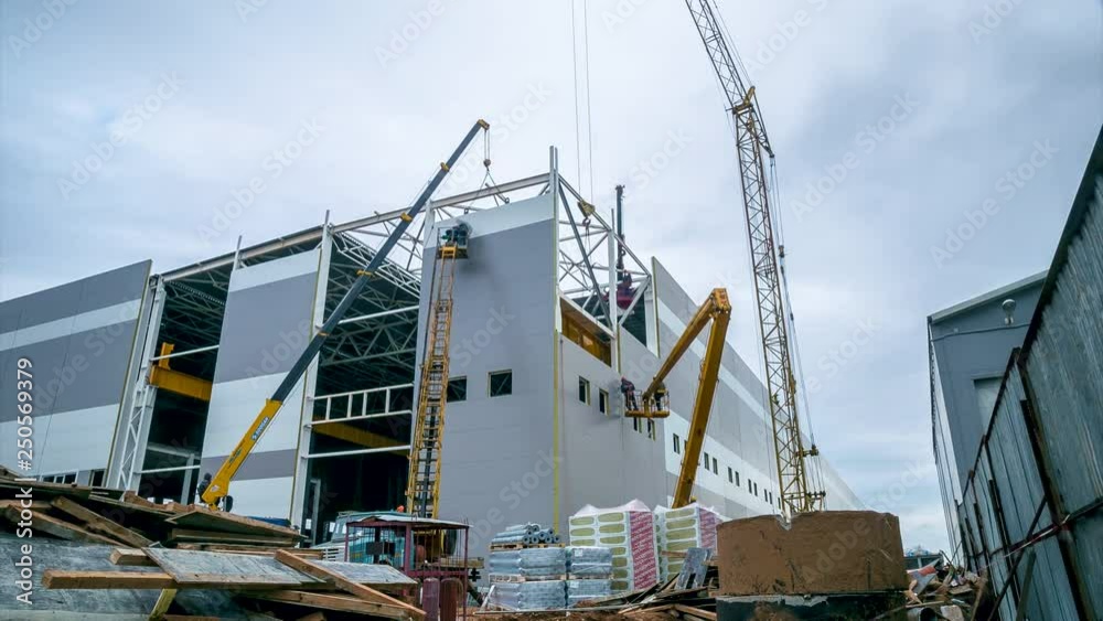 timelapse construction of storehouse with cranes against sky