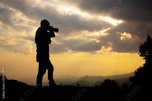 silhouette of a photographer who shoots a sunset in the mountains