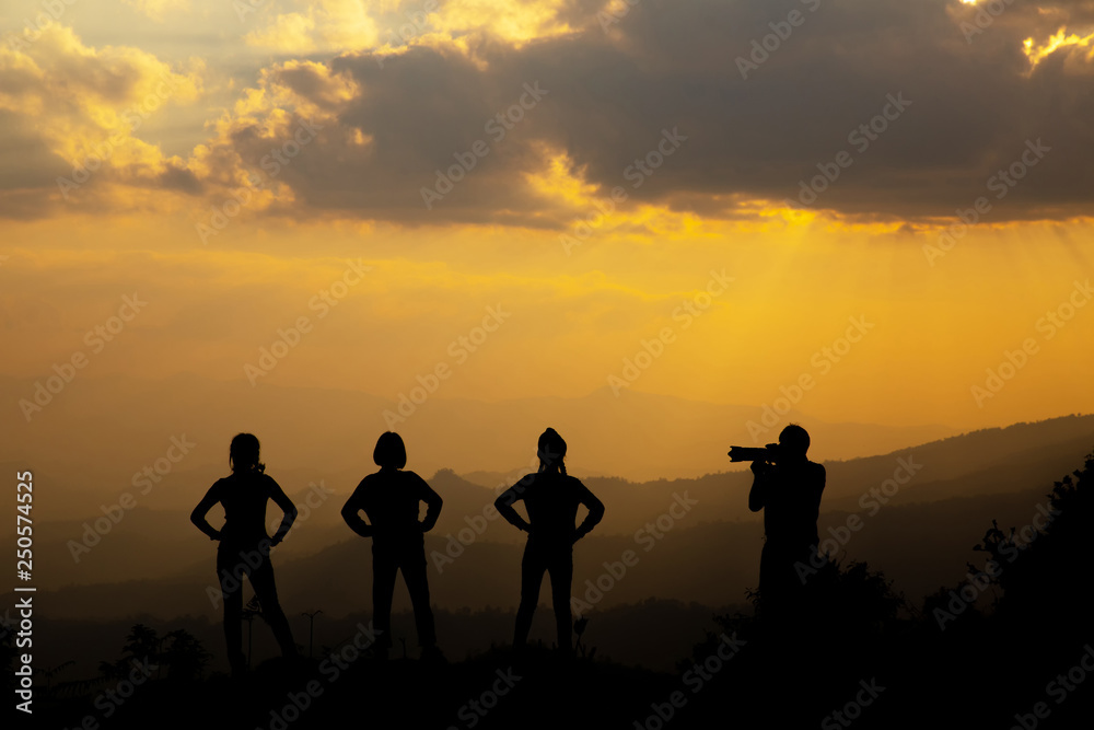 Group of happy people photographing in the mountain at sunset, concept about having fun on the hill, silhouette