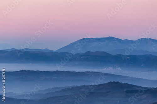 Beautifully colored sky at dusk, with mountains layers and mist between them