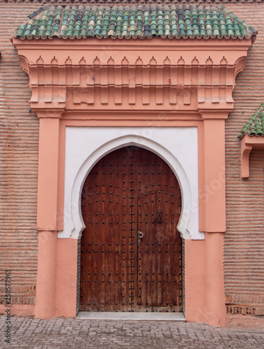 Traditional Moroccan style design of an ancient wooden entry door. In the old Medina of Marrakech, Morocco. Typical, old, brown intricately carved, studded, Moroccan riad door © mitzo_bs