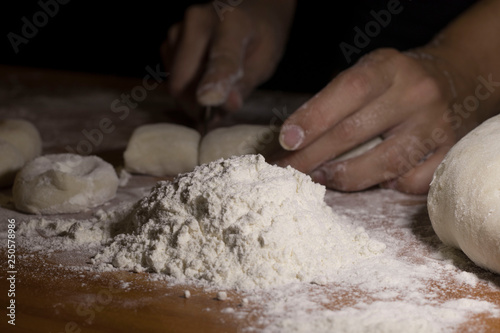 women's hands cut the dough on the table floured