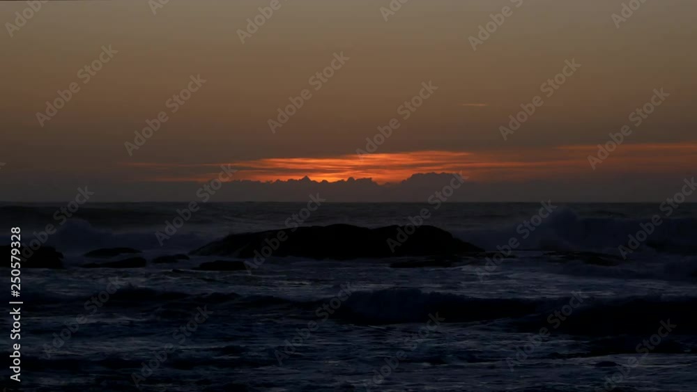 Time lapse sun setting below the horizon over ocean with rough waves Time lapse sun setting below the horizon over ocean with rough waves