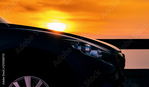 Side view of SUV car with sport and modern design parked on concrete road by the sea at sunset. Hybrid and electric car technology. Travel on vacation at the beach. Road trip. Automotive industry. © Artinun