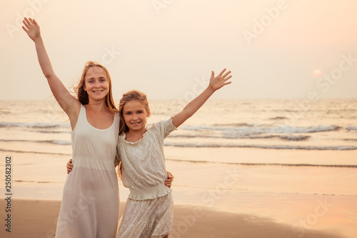 Little teenager cute girl and young mother at tropical beach enjoying the sunset on the sea tenderness and intimacy care