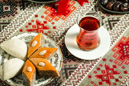 Novruz setting table decoration, tea in  tulip shape glass on ethnic motives rustic table cloth with wheat grass, dyed eggs, traditional sweets, samovar, new year spring celebration, nature awakening