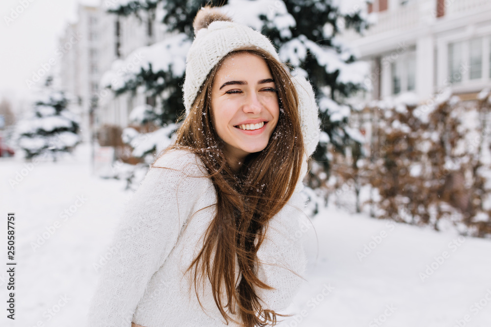 Close-up portrait of happy girl in woolen sweater enjoying winter moments. Outdoor photo of long-haired laughing lady in knitted hat having fun in snowy morning on blur nature background. Close-up portrait of happy girl in woolen sweater enjoying winter moments. Outdoor photo of long-haired laughing lady in knitted hat having fun in snowy morning on blur nature background.