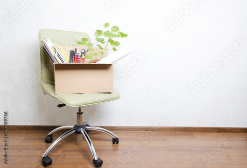 Box with personal items standing on the chair in the office.Concept of moving or dismissal photo