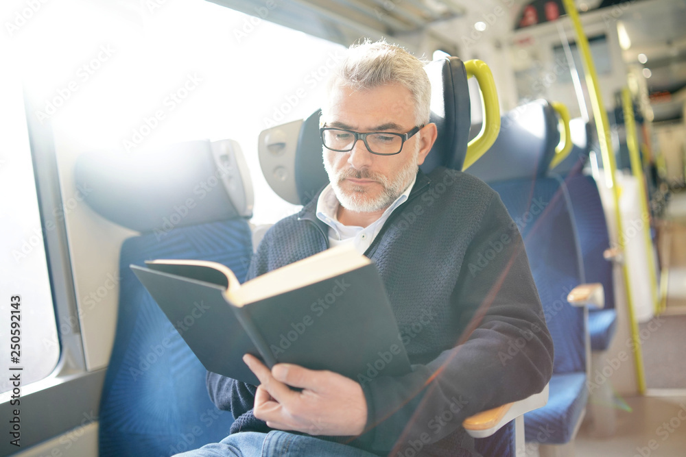 Mature man reading book while traveling on a train Mature man reading book while traveling on a train