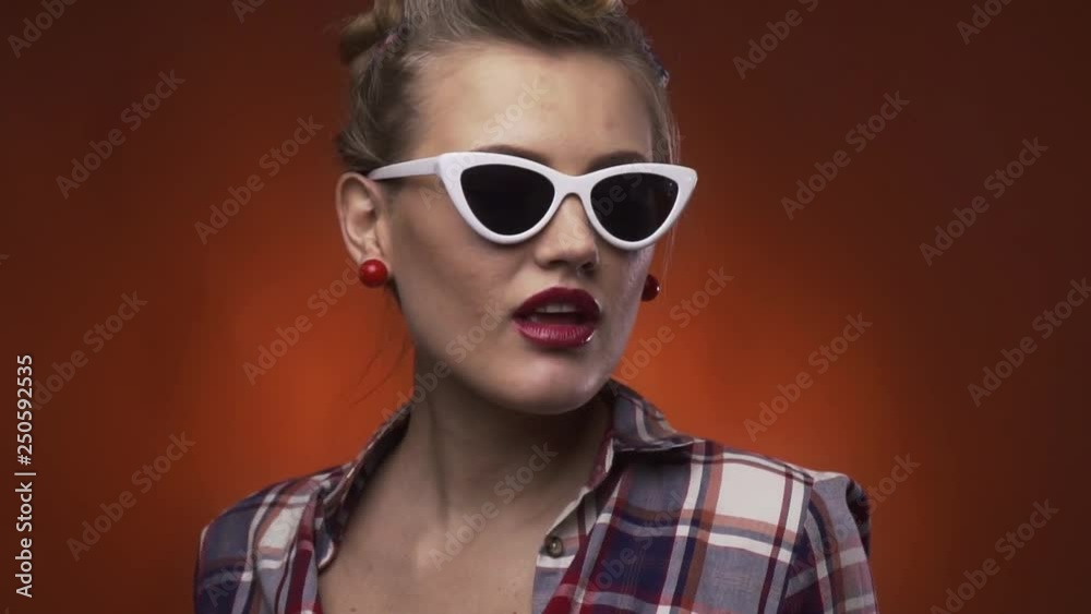Gorgeous retro girl with red lipstick and white glasses is adjusting the collar of her shirt Gorgeous retro girl with red lipstick and white glasses is adjusting the collar of her shirt