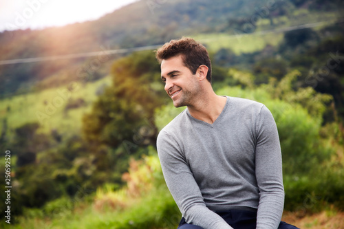 Smiling man in grey with stubble, looking away