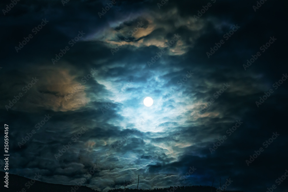 Full moon or supermoon in night blue sky with clouds, dramatic mysterious atmosphere