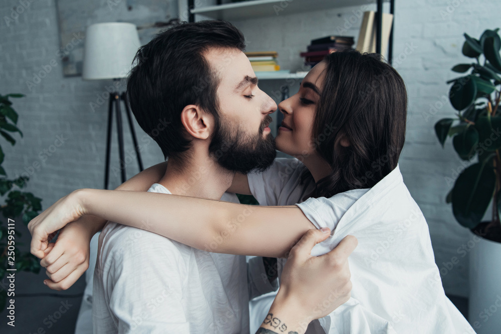 Fototapeta premium beautiful romantic young couple looking at each other and hugging at home