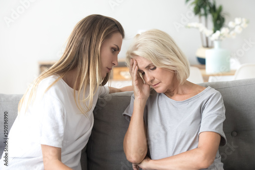 Loving daughter comforting  consoling aged upset mother at home