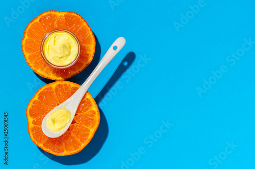 Face cream and orange on a bright blue background. Cosmetics from natural ingredients natural concept