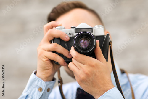 photography concept - close up of male photographer with film camera making shot outdoors