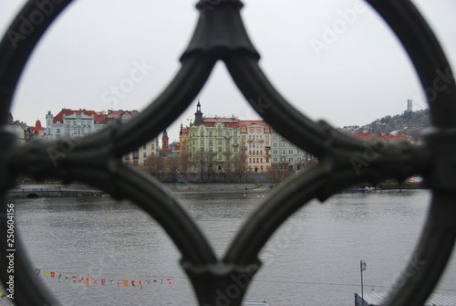Historical colorful building on embankment in Prague and Moldau river, view through old railing 