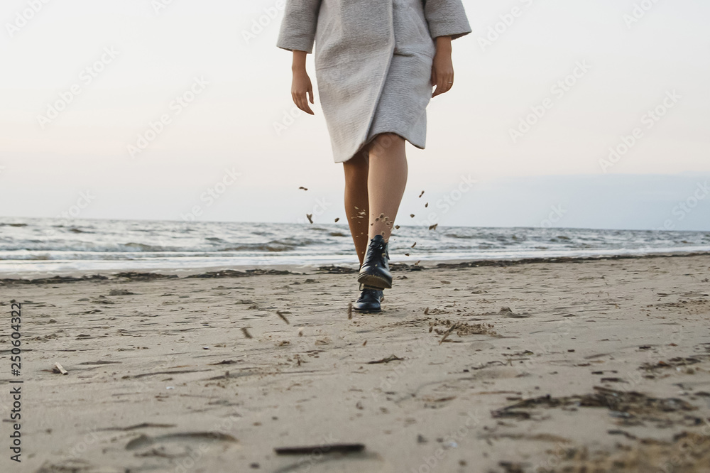 Carefree woman in black leather boots kick sand on beach. Flying wet sand.  Concept footwear protection, water and dust resistance. Stock-Foto | Adobe  Stock