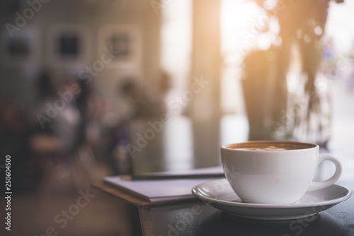 Cappuccino cup on the table with blur people in coffee shop background  vintage tone 