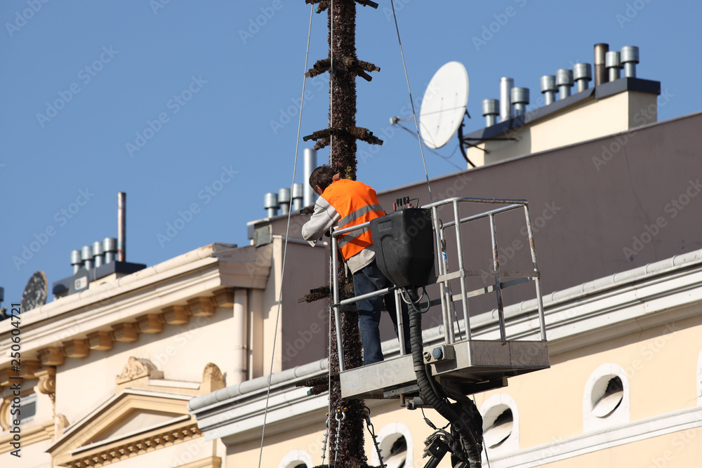 The worker in overalls works at height in a building mechanical lifting basket. Repair and construction work on the renovation of architectural monuments in the historic part of the city. Installation