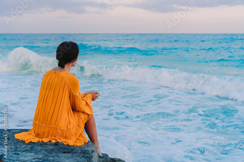 Young beautiful woman in sunset background of ocean
