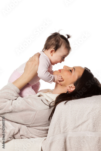 A happy young mom plays with her baby daughter on a white background