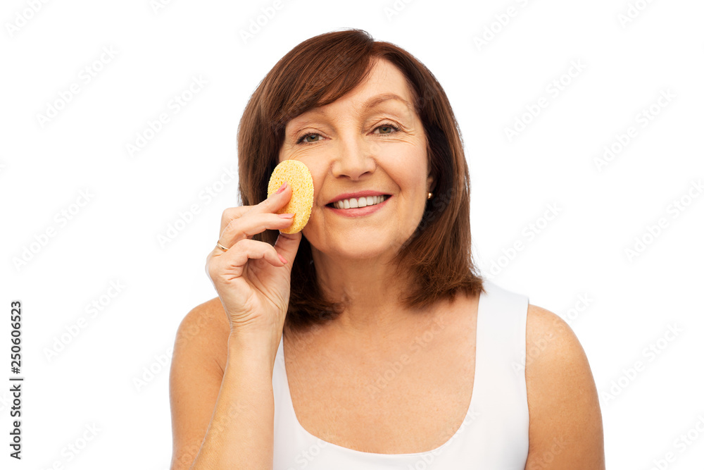 beauty, skin care and old people concept - smiling senior woman cleaning her face with exfoliating sponge over white background beauty, skin care and old people concept - smiling senior woman cleaning her face with exfoliating sponge over white background
