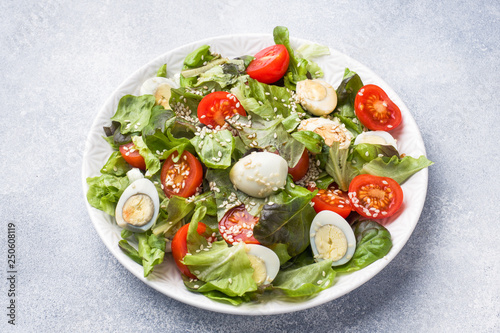 Fresh salad with tomatoes and quail eggs and lettuce.