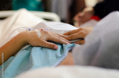 patient in hospital bed with an IV line in her hand waiting for surgery