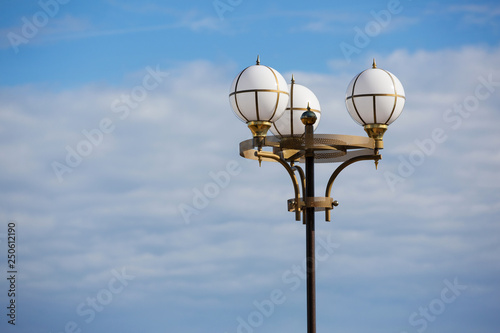 street lamp with round lamps against the sky with clouds