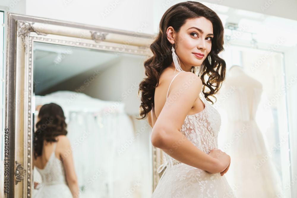 Naklejka premium Beautifu bride choosing wedding dress in a wedding salon