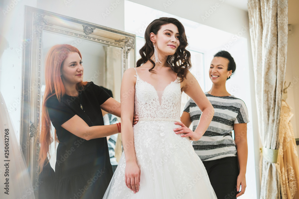 Naklejka premium Beautifu bride choosing wedding dress in a wedding salon
