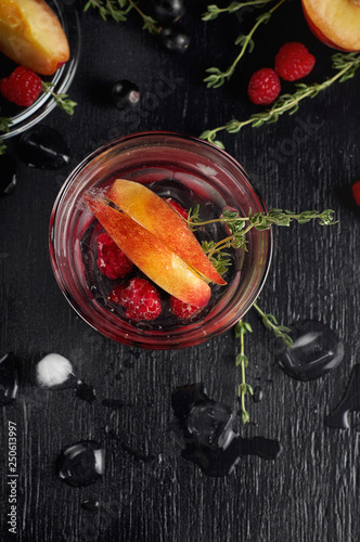 Raspberry thyme gin and tonic cocktail with blackcurrant and peaches