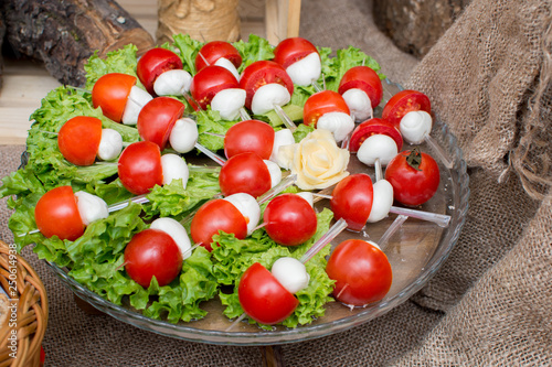  cherry tomatoes and mozzarella cheese on a stick on a pillow of salad