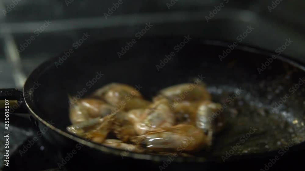 Сhef in the kitchen prepares shrimp on a hot pan sprinkling them with spices and pouring sauce Сhef in the kitchen prepares shrimp on a hot pan sprinkling them with spices and pouring sauce