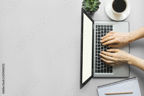 Woman typing by laptop on office pink table. Space for text.